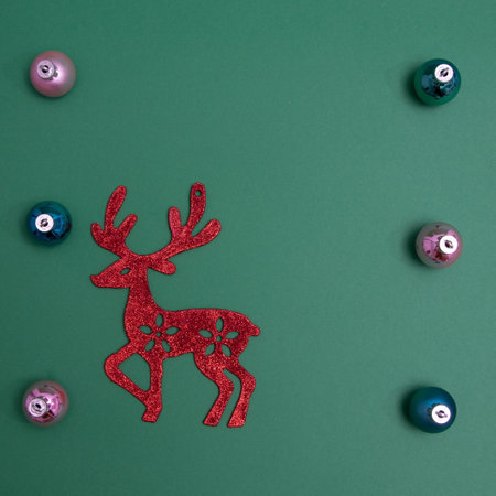 New Year's decorations in various colors with red reindeer on a green background with copy space. Minimalistic flat lay scene.の写真素材