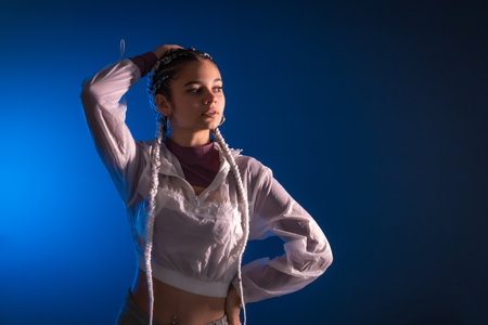 Urban session. Young caucasian woman with long white braids on a blue plain background, rap or trap dancer, alternative posingの写真素材