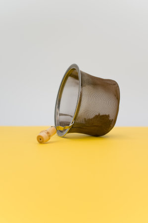 metal tea strainer on a yellow tabletop background with text spaceの写真素材