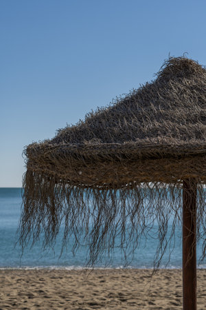 straw umbrellas on the beach on a sunny day sea in the backgroundの写真素材