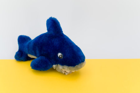 isolated blue fish plush toy on a yellow tabletop with copy spaceの写真素材