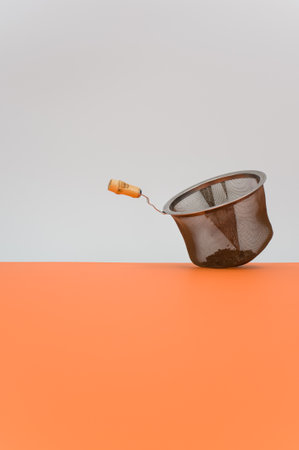 metal tea strainer on a orange tabletop background with text spaceの写真素材