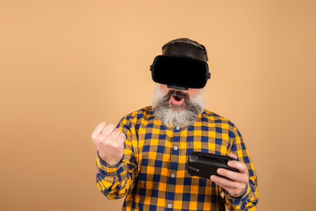 Cheerful man in 3D glasses plays with a joystick on a yellow backgroundの写真素材