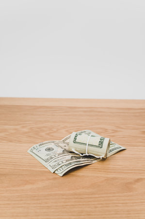 US dollar banknotes rolled up on a wooden tabletop with text spaceの写真素材