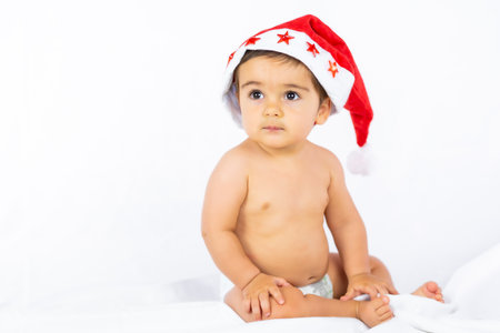 A baby boy with a red Christmas hat on a white background, copy space, portrait of the child with the Santa hatの写真素材