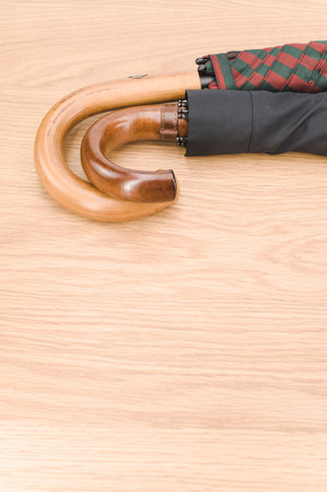 black and colorful umbrellas with solid wood handle on a wooden surface with copy spaceの写真素材