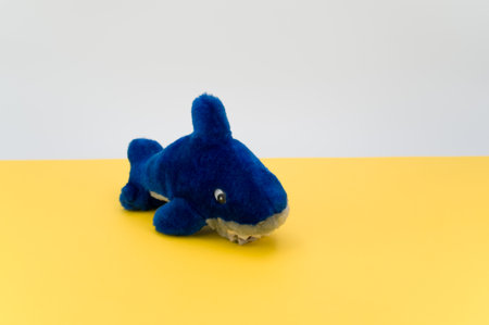 isolated blue fish plush toy on a yellow tabletop with copy spaceの写真素材