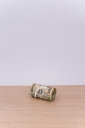 US dollar banknotes rolled up on a wooden tabletop with text spaceの写真素材