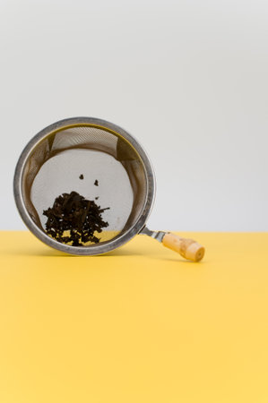 metal tea strainer on a yellow tabletop background with text spaceの写真素材