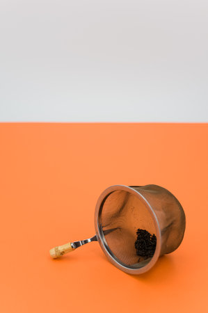 metal tea strainer on a orange tabletop background with text spaceの写真素材