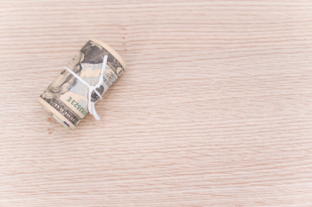 US dollar banknotes rolled up on a wooden tabletop with text space