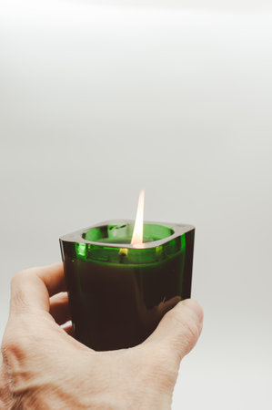 burning green scented candle in a glass on a white surface with copy spaceの写真素材
