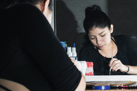 beautiful latina woman in front of the mirror making up her eyes. girl taking makeup powder from her...