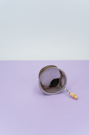 metal tea strainer on a lilac tabletop background with text spaceの写真素材