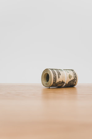 US dollar banknotes rolled up on a wooden tabletop with text space