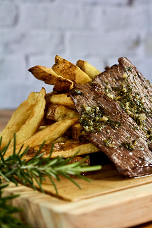 roast meat dipped in chimichurri with fries on a board, saladの写真素材