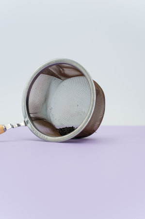 metal tea strainer on a lilac tabletop background with text space