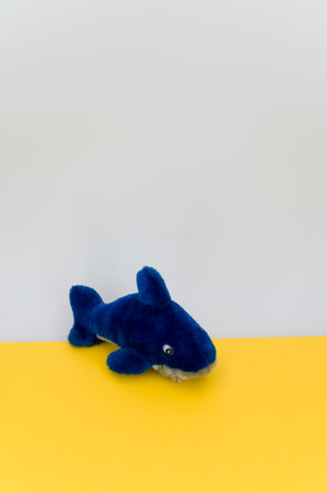 isolated blue fish plush toy on a yellow tabletop with copy spaceの写真素材