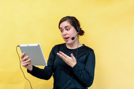 Happy woman talking through a video chat, isolated over yellow background.の写真素材