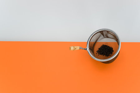 metal tea strainer on a orange tabletop background with text spaceの写真素材