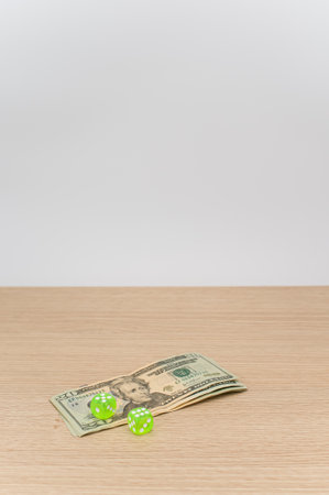 US dollar currency banknotes and dice on a wooden background with copy space