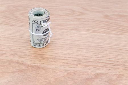 US dollar banknotes rolled up on a wooden tabletop with text spaceの写真素材