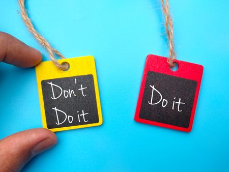 Hand holding wooden board written with text Don't Do it,Do it on blue background.の写真素材