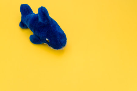 isolated blue fish plush toy on a yellow tabletop with copy spaceの写真素材