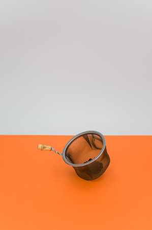 metal tea strainer on a orange tabletop background with text spaceの写真素材