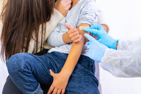 Scared child after vaccination injection by a female doctor. Vaccination of children. Immunization in the coronavirus pandemic, covid-19の写真素材