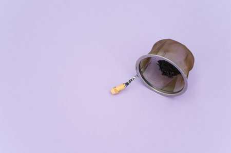 metal tea strainer on a lilac tabletop background with text space