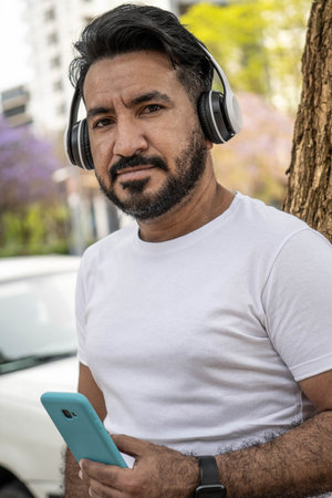 portrait of latin man with headphones in the city looking at cameraの写真素材