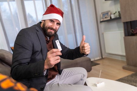 Happy after the negative test result in his living room to go to Christmas dinner. Man doing the rapid antigen test virusの写真素材