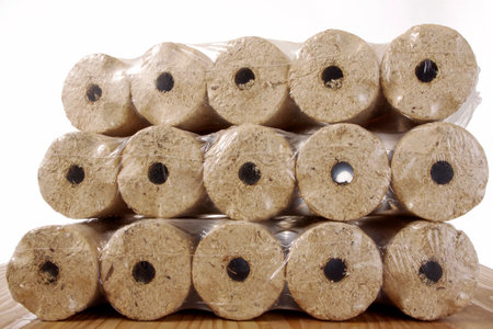 Round wooden briquettes wrapped in plastic film isolated against a white backgroundの写真素材
