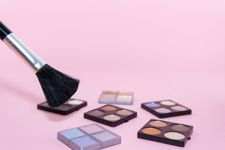 Make-up set with various colors and a brush on pink background. Beauty conceptの写真素材