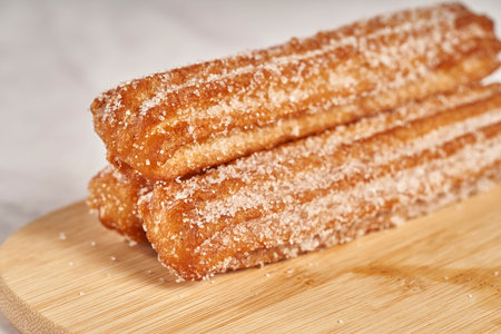 three churros with sugar on a wooden boardの写真素材