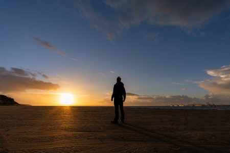 Young man standing watching sunset on beach
