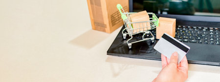 Woman hand holding credit card with using laptop for online shopping while making orders at home.の写真素材