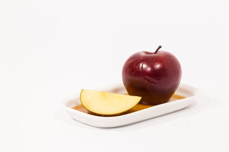 Red apple and red apple slice on white plate with honey isolated on a white background. Symbols of...