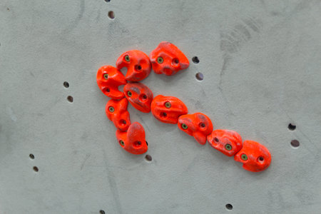 Red climbing holds in the shape of an arrow on grey wallの写真素材