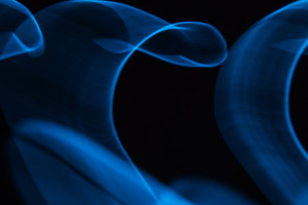 Glowing abstract curved lines.Blue colors.Black background.Done by long exposure technique.の写真素材