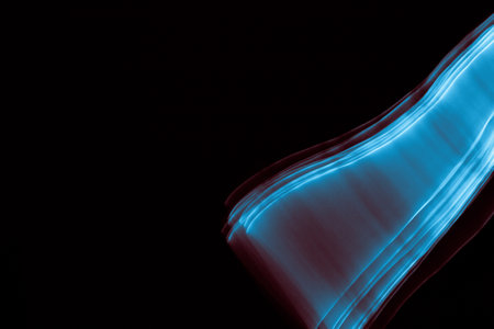 Light painted glowing abstract blue and red curved lines on a black backgroundの写真素材