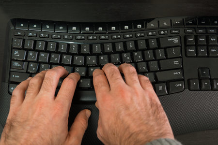 Man typing on a keyboard with letters in Hebrew and English - Wireless keyboard - Top Viewの写真素材