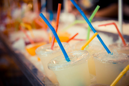 Selection of plastic cups with grapefruit juice and colored straws.の写真素材