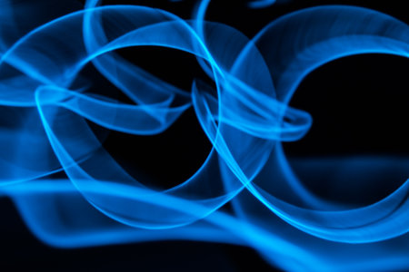 Glowing abstract curved lines.Blue colors.Black background.Done by long exposure technique.の写真素材