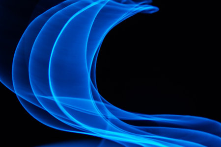 Glowing abstract curved lines.Blue colors.Black background.Done by long exposure technique.の写真素材
