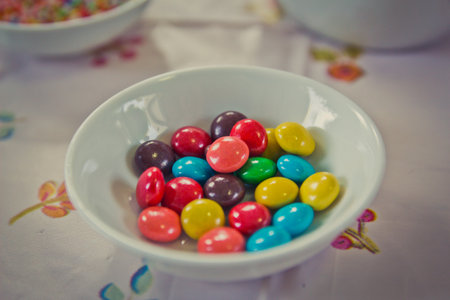 Colorful candy sprinkles and chocolate chips in ceramic bowlの写真素材