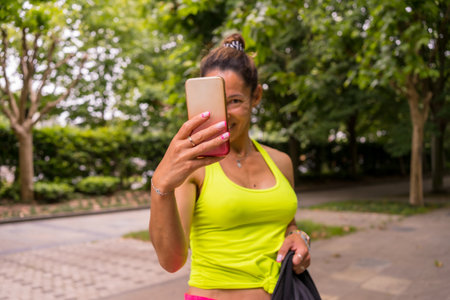 Latin girl doing sports in a park in the city, lifestyle a healthy life, two very happy girls taking pictures after finishing the exerciseの写真素材