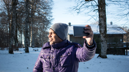 A young man on vacation in snow taking selfie with his smart phoneの写真素材