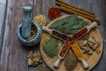 different types of spices in wooden spoon and mortar for their preparation out of focusの写真素材